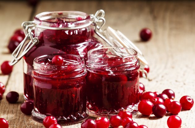 Delicious cranberry jam in glass jars and fresh cranberry