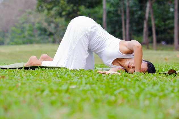 Beautiful woman practicing yoga in the park.Thread The Needle.
