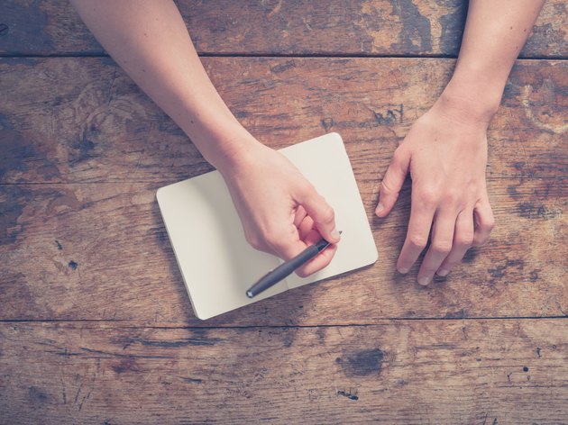 Woman writing in notepad at wooden table