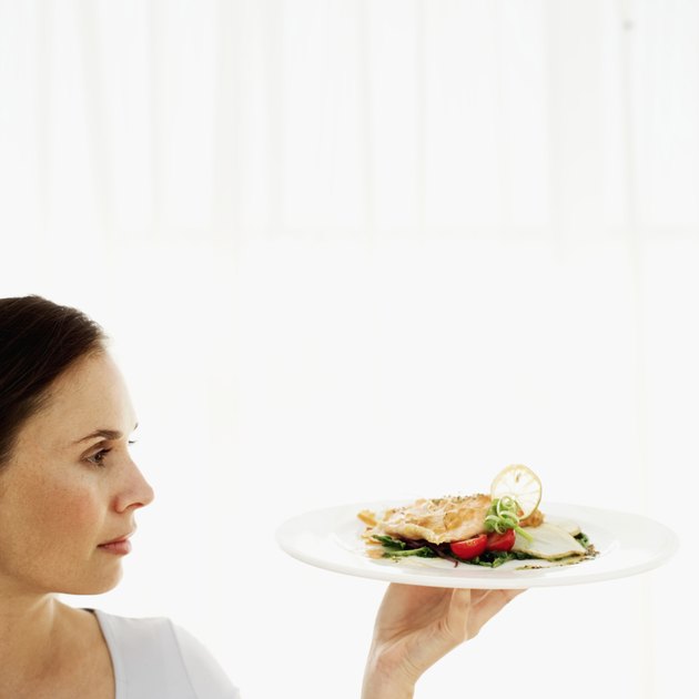 Young woman holding up a plate of grilled salmon