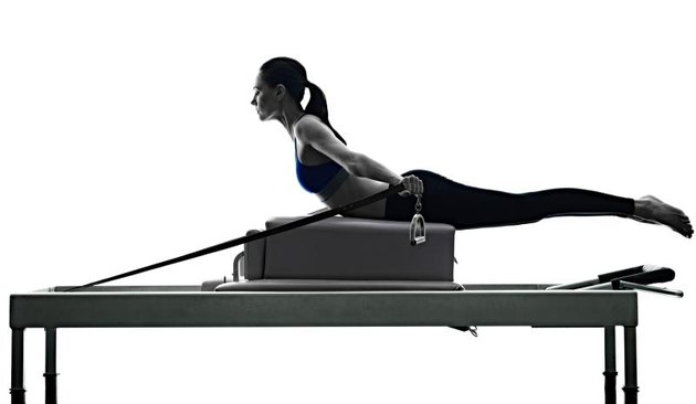 one caucasian woman exercising pilates reformer exercises fitness in silhouette isolated on white backgound