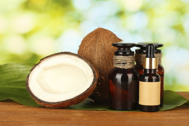 coconut oil in bottles with coconuts on green background