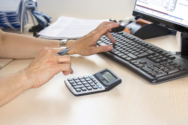 Businesswoman typing on calculator