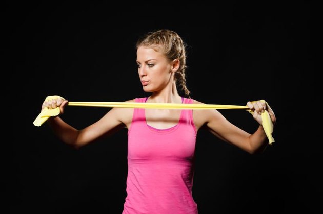 Beautiful young woman is exercising with rubber band.