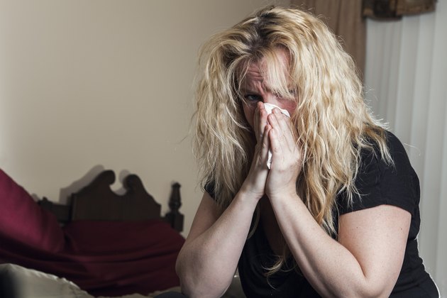 Young woman having flu, feeling bad, blowing her nose