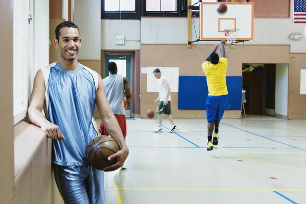 Portrait of a young man holding a basketball in a basketball court