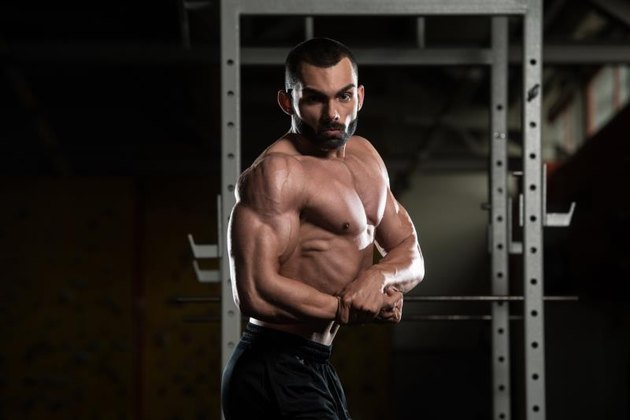 Portrait Of A Young Physically Fit Man Performing Side Chest Pose - Muscular Athletic Bodybuilder Fitness Model Posing After Exercises