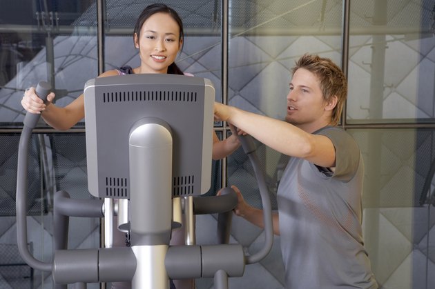 Man helping a woman in the gym.