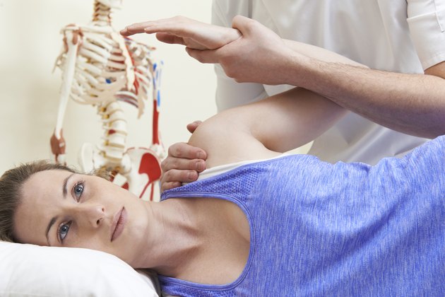 Male Osteopath Treating Female Patient With Shoulder Problem