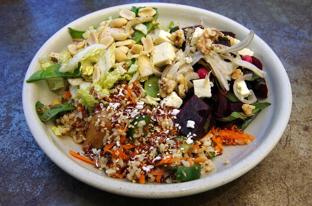 Three salads arranged on a round plate set on a rusted and scratched metal table top