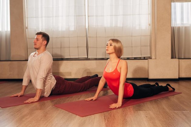 young woman and man doing yoga exercise Cobra in special studio