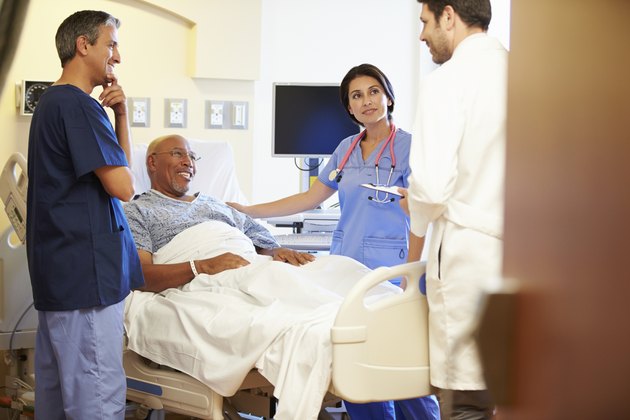 Medical Team Meeting With Senior Man In Hospital Room