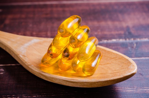 Fish oil on wooden spoon with wooden background