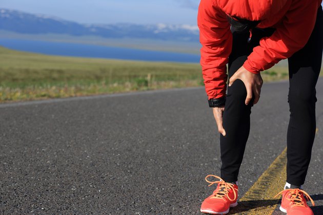woman runner hold her injured leg on road