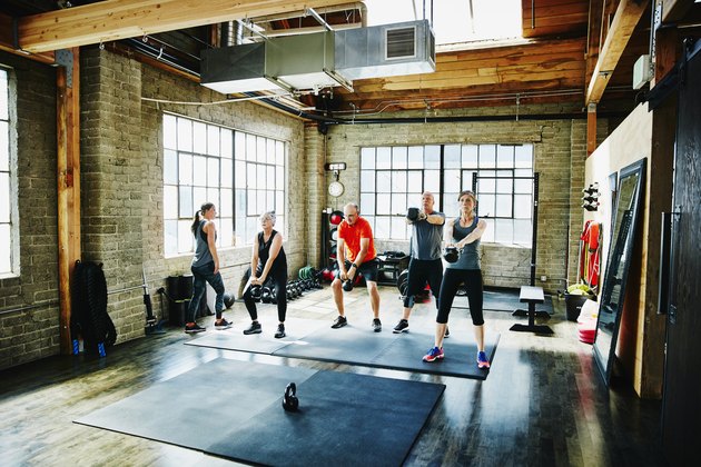 Athletes doing kettle bell swings during class