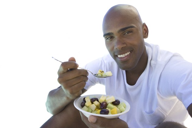 man sitting down eating bowl of fruit, cut out