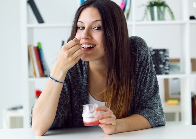 Beautiful young woman eating yogurt at home.