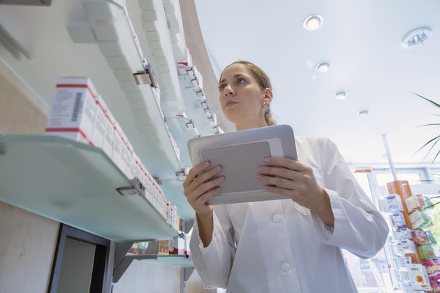 Pharmacist in pharmacy holding digital tablet