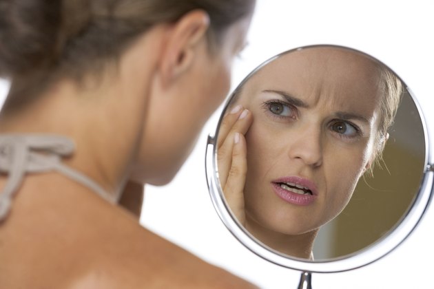 concerned young woman looking in mirror
