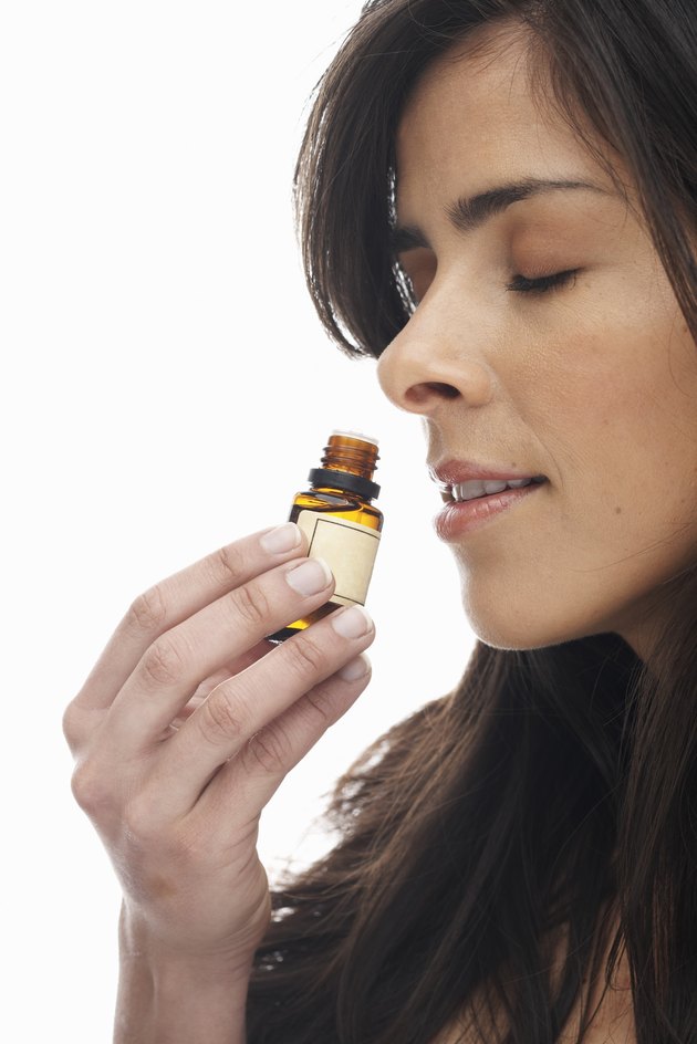 Young woman smelling aromatherapy oil, eyes closed