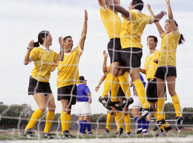 Mixed Football team celebrating goal at goal mouth, surface view