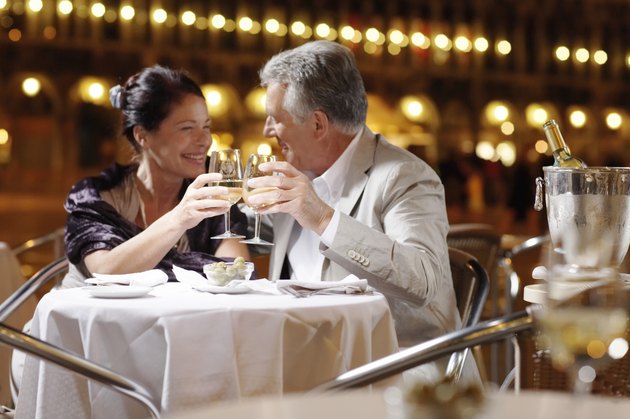 Couple at restaurant in square, toasting drinks, smiling, night