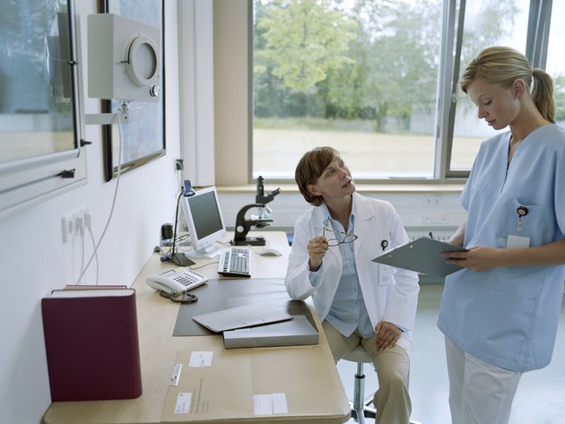 Female doctor talking to young female nurse indoors
