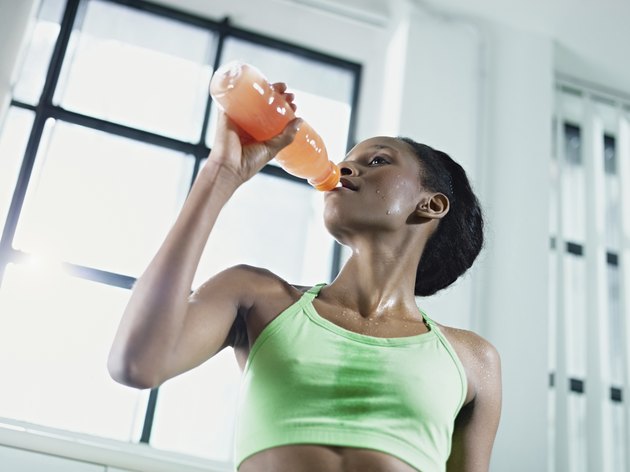 african woman in gym drinking energy drink