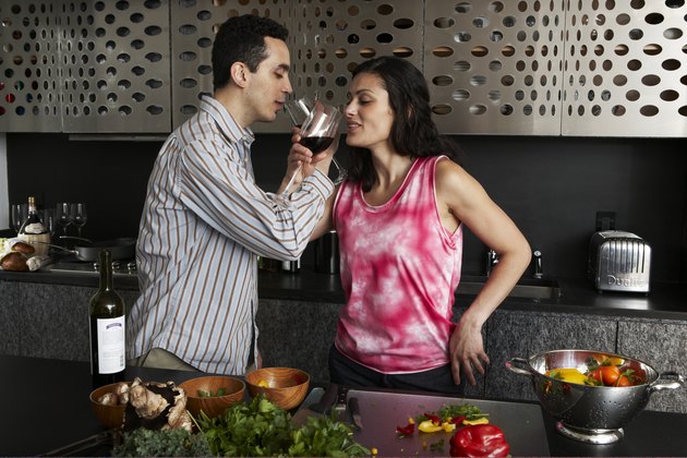 Drinking wine while preparing meal in kitchen