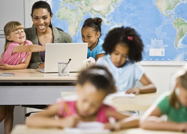 Mixed Race female teacher and students looking at laptop