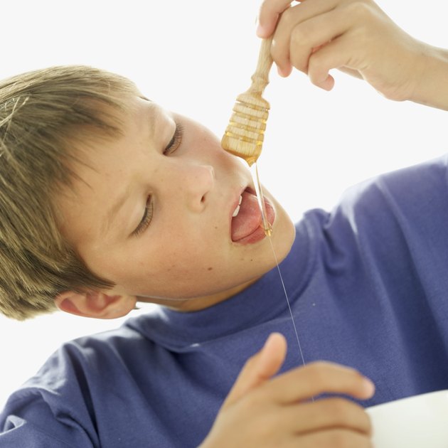 close-up of a boy dropping honey on his tongue