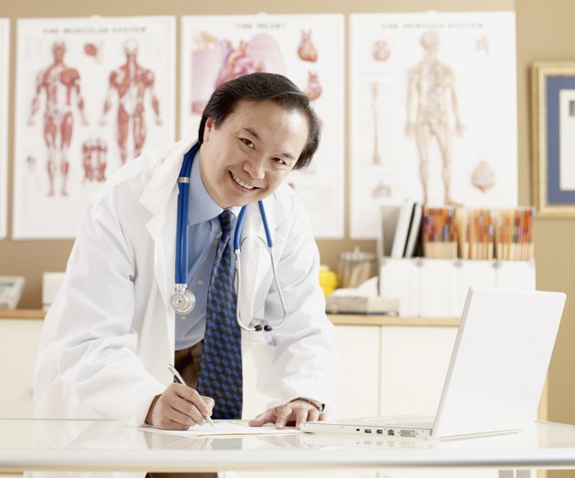 Asian male doctor writing at desk