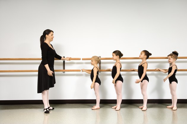 Ballet instructor demonstrating for students standing at the barre