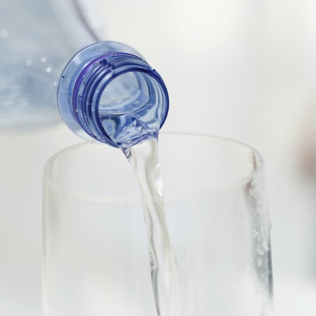 close-up of water flowing out of a bottle into a glass