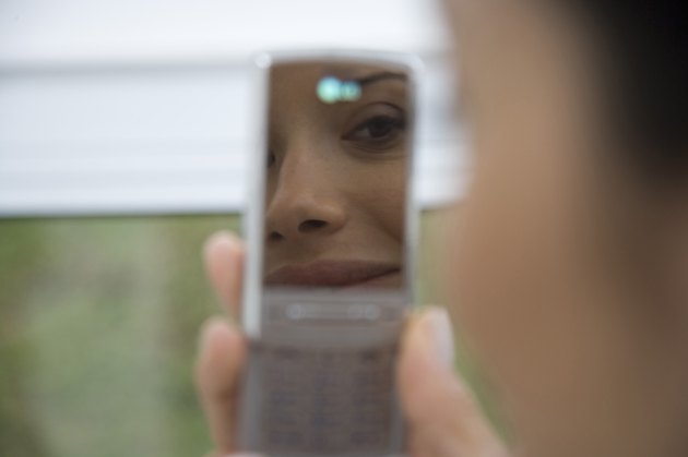Reflection of young woman in mobile phone