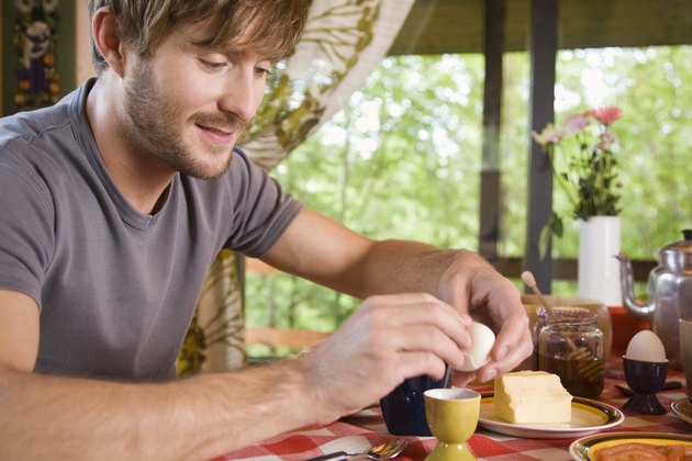 Man peeling shell of hard-boiled egg