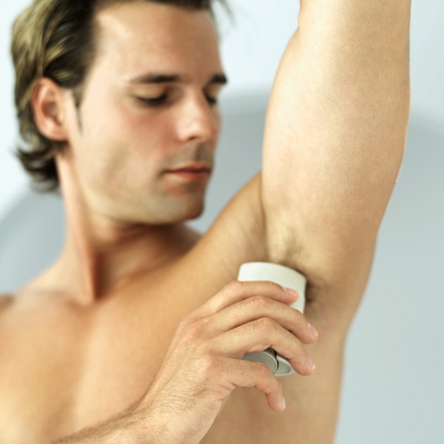 man applying deodorant to his armpit