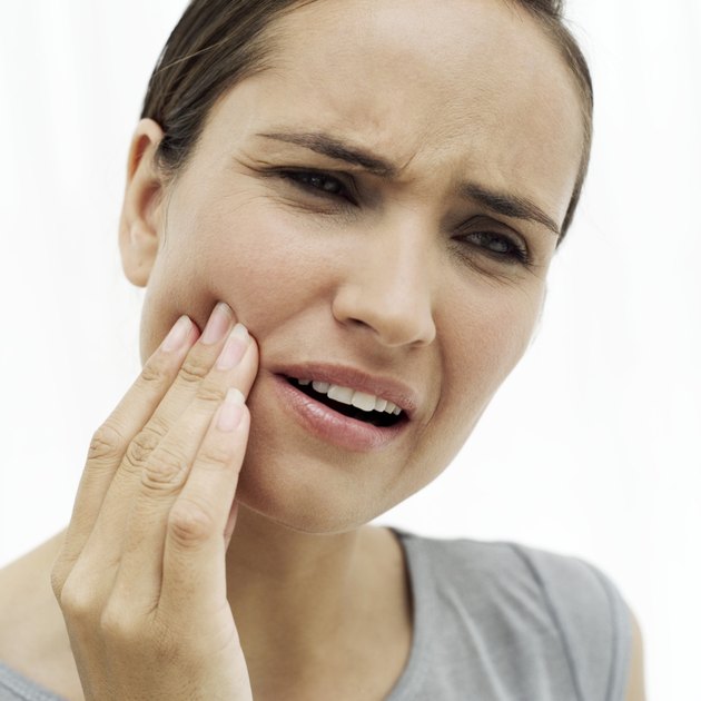 close-up of a young woman holding her cheek in pain