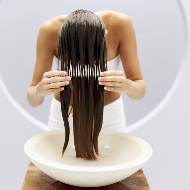 woman combing wet hair over a washbasin