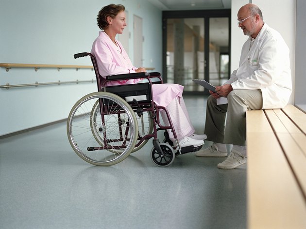 Mature male doctor talking to female patient in wheelchair