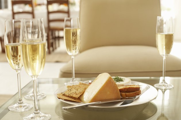 Glasses of wine by plate of cheese and biscuits on coffee table