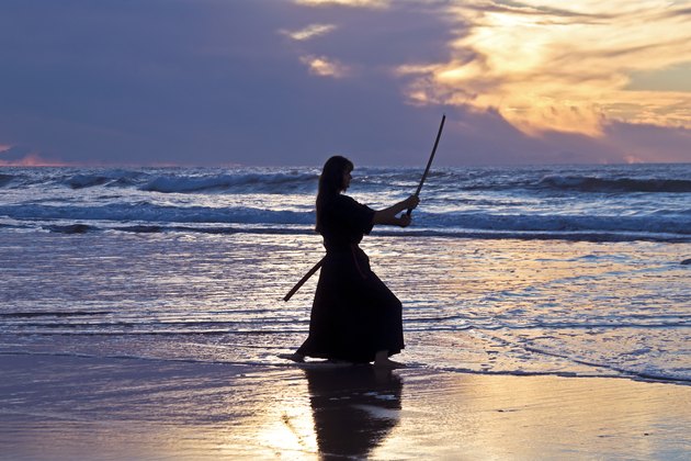 Young samurai women with Japanese sword(Katana) at sunset on the