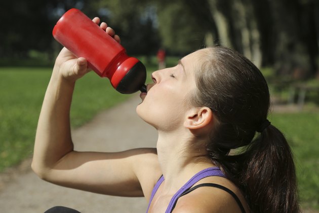 Attractive sporty woman drinking water after sports