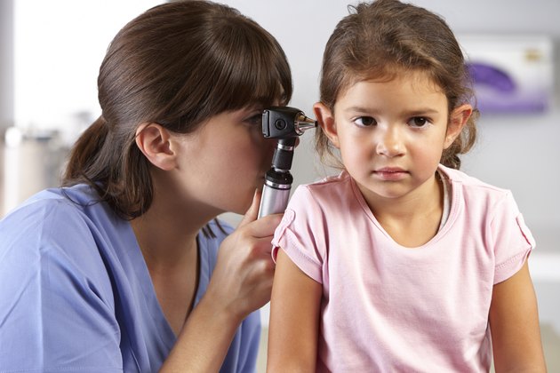 Doctor Examining Child's Ears In Doctor's Office