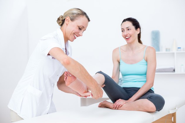 Doctor bandaging her patient ankle