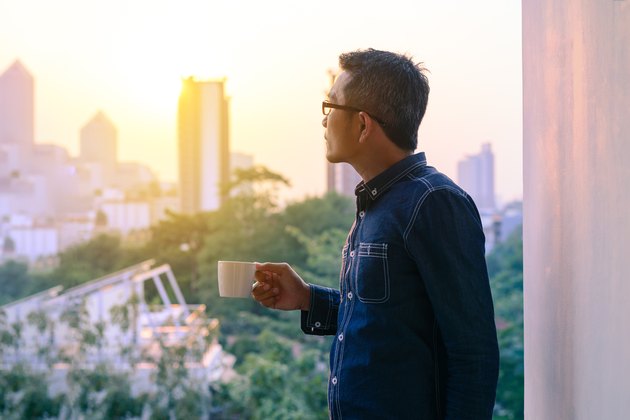 Businessman in denim jacket and glasses drinking hot coffee.