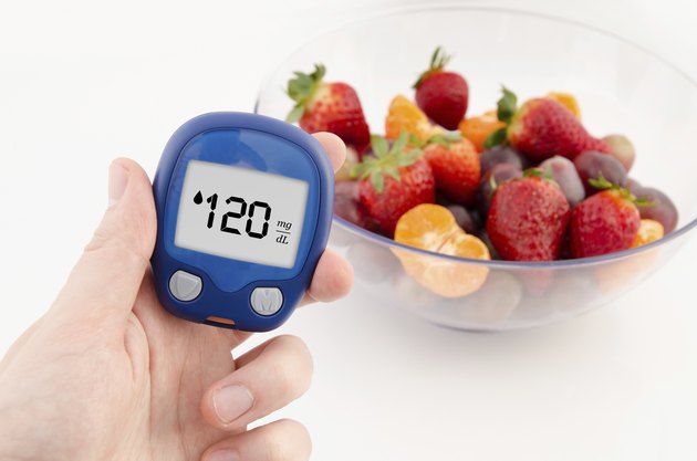 Hand holding meter. Diabetes doing glucose level test. Fruits in