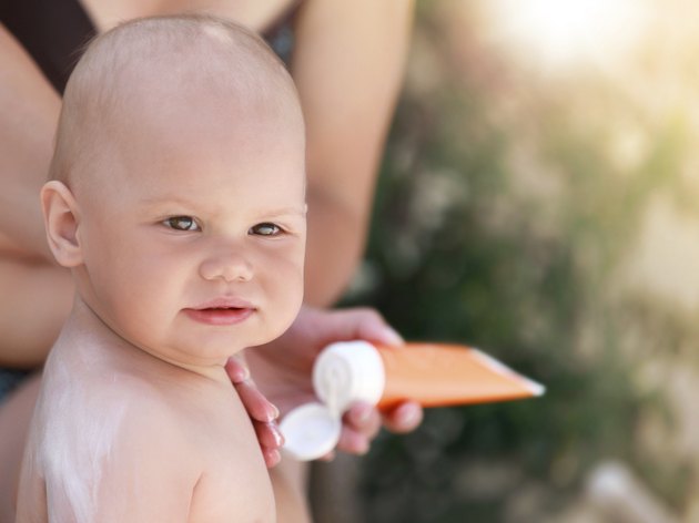 Caucasian mom does sunblock on her baby in the air