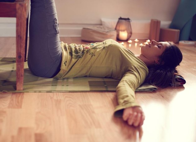 Serene lady relaxing and meditating on a yoga mat in a cosy house