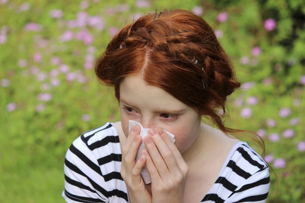 Girl in flower gardens with hayfever, blowing nose, sneezing, allergies